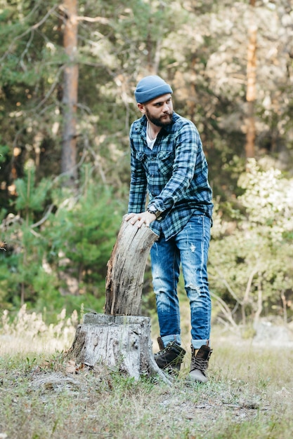 Stylish bearded forester chopping wood with an axe