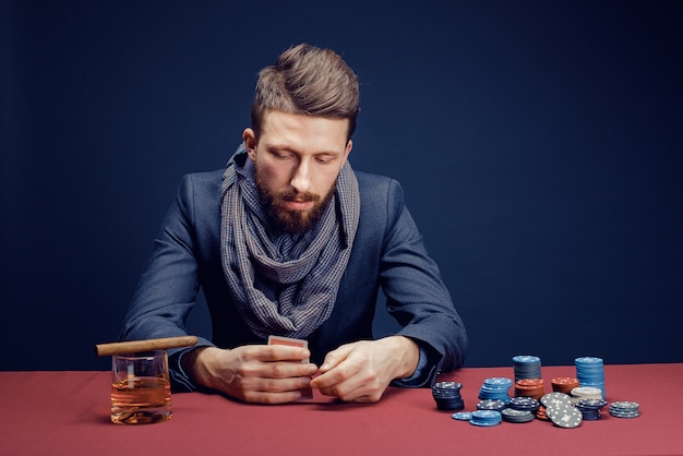 Stylish bearded man playing in dark casino