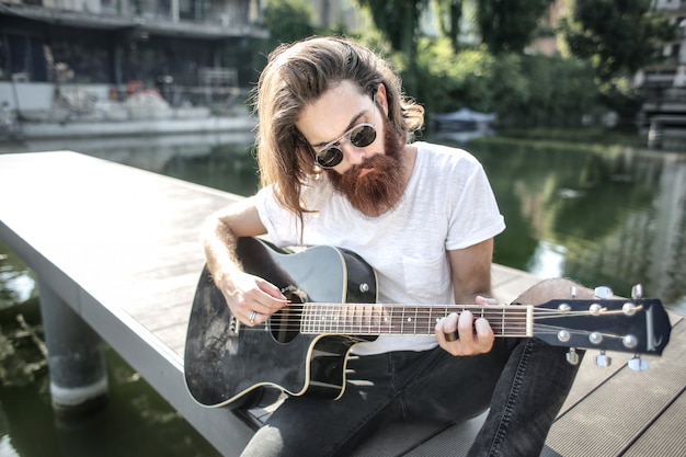 Stylish bearded man playing on a guitar