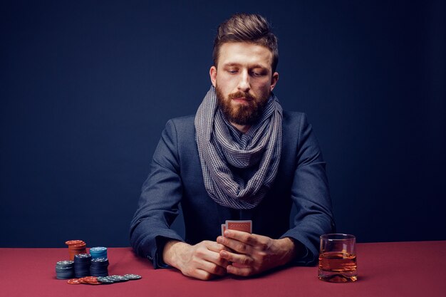 Stylish bearded Man in suit and scarf playing in dark casino