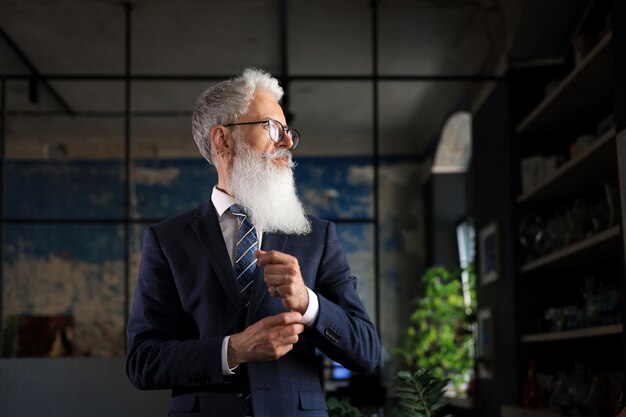 Stylish bearded man in a suit standing in modern office.