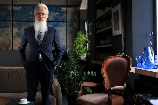 Stylish bearded man in a suit standing in modern office.