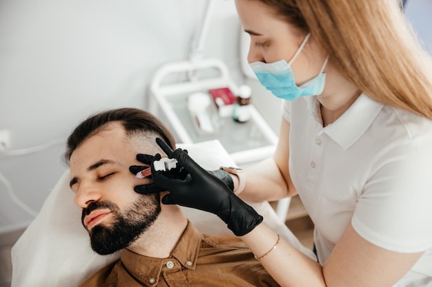 Stylish bearded man visiting aesthetic clinic getting lips filler closeup