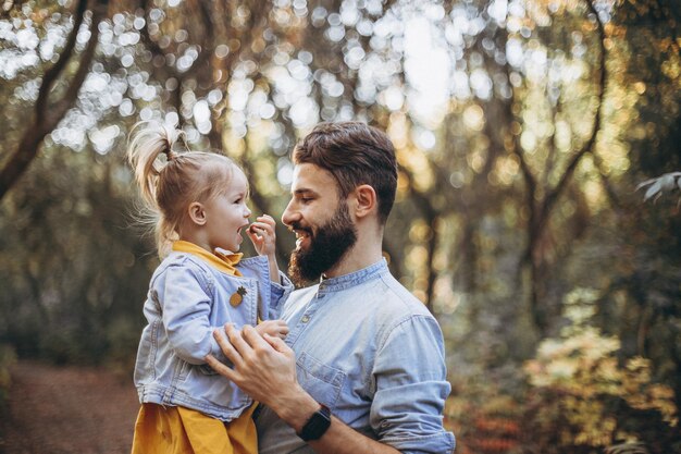 stylish bearded man walking in the autumn park together with his sweet daughter enjoying spring
