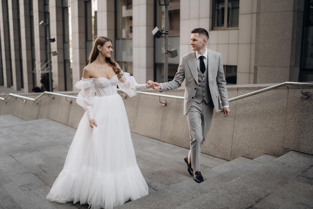 Stylish beautiful couple European newlyweds go up the stairs on the day of their wedding