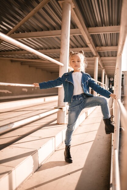 Stylish beautiful girl of about seven in a denim jacket walks on the street