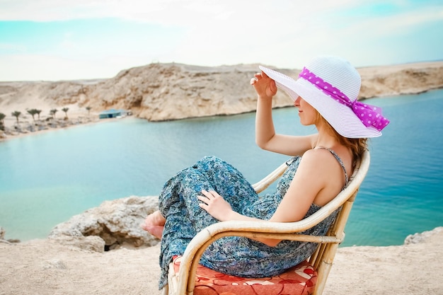 Stylish beautiful girl in hat on chair background