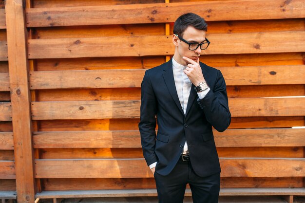 Stylish, beautiful, man in classic costume , posing near wooden wall.