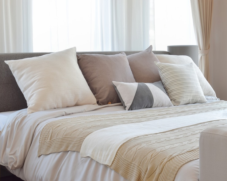 Photo stylish bedroom interior design with brown patterned pillows on bed and decorative table lamp.