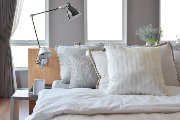 Stylish bedroom interior design with white striped pillows on bed and decorative table lamp.