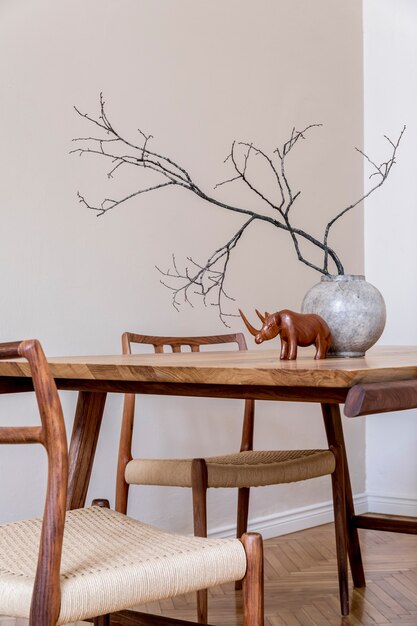 Stylish beige interior of modern dining room with design wooden oak table and chairs, vase with flowers, elegant rattan accessories and decoration. Korean style of home decor.