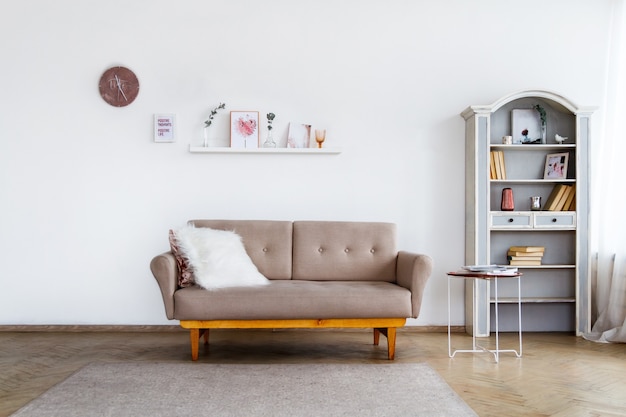 A stylish beige sofa with a white fluffy pillow