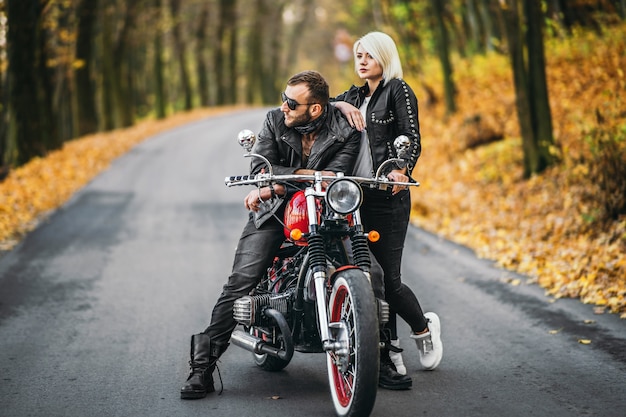 Elegante coppia in bicicletta con una motocicletta rossa