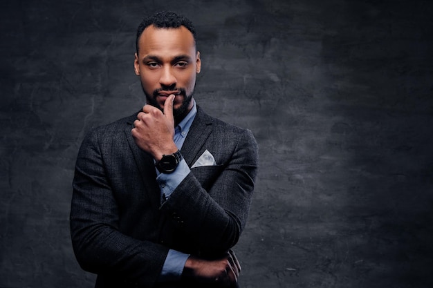 A stylish black American male dressed in a suit over grey background.