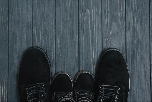 Stylish black boots for men on a wooden background