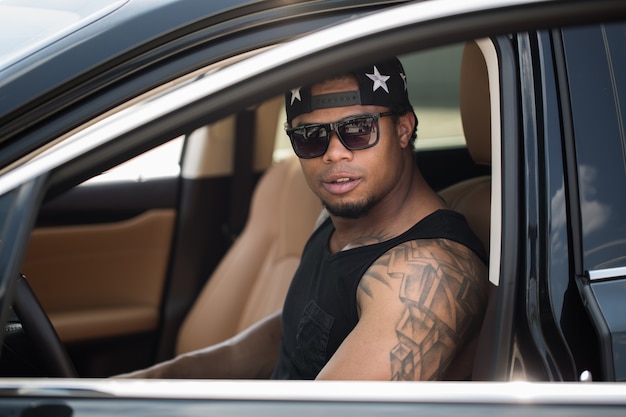 Stylish black man sitting behind the wheel of luxury car.