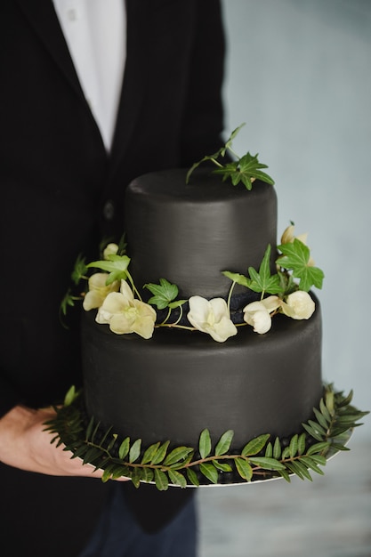 사진 신랑의 손에 세련된 검은 웨딩 케이크