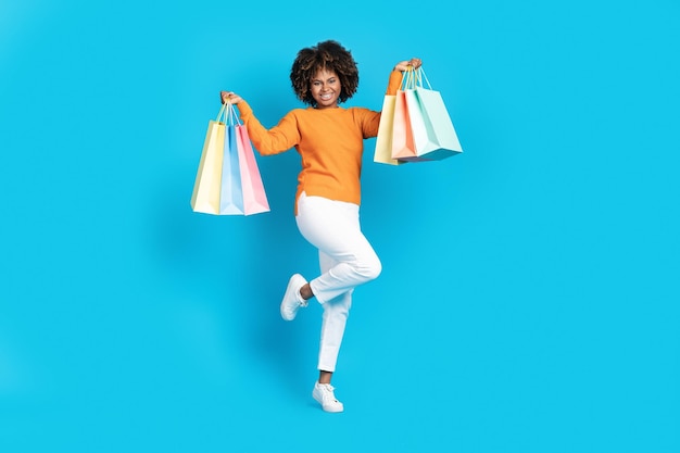 Stylish black woman shopaholic dancing with shopping bags