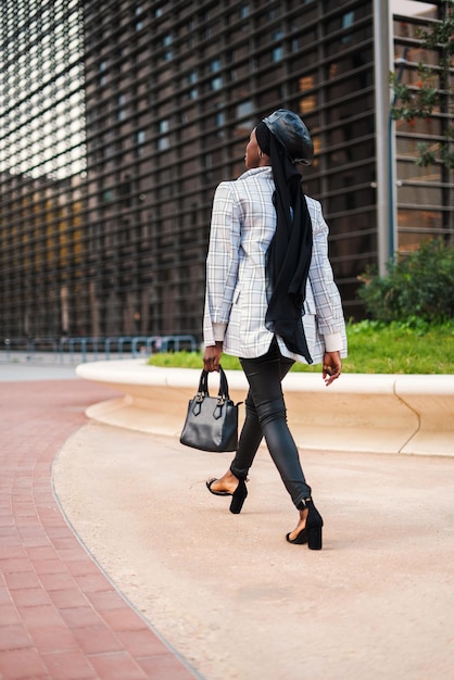 Stylish black woman walking in park in downtown