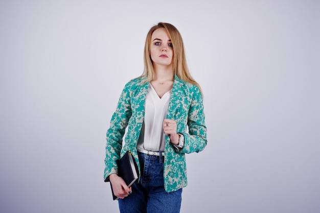 Elegante ragazza bionda in giacca e jeans con diario del taccuino a portata di mano su sfondo bianco in studio