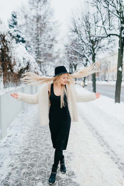 Stylish blonde girl with long flying hair posing in the street