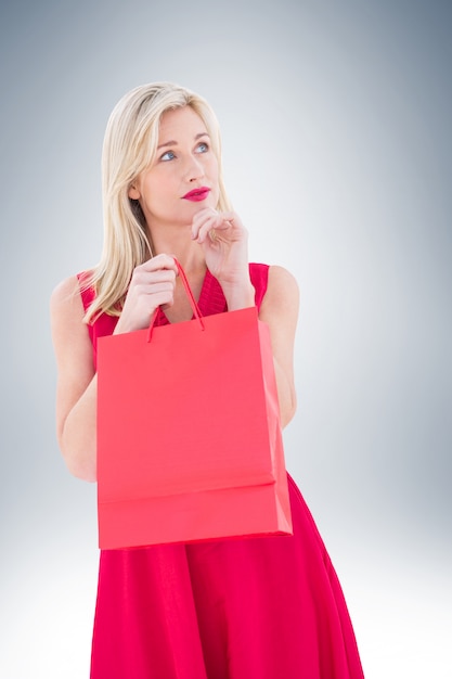 Stylish blonde in red dress opening gift bag