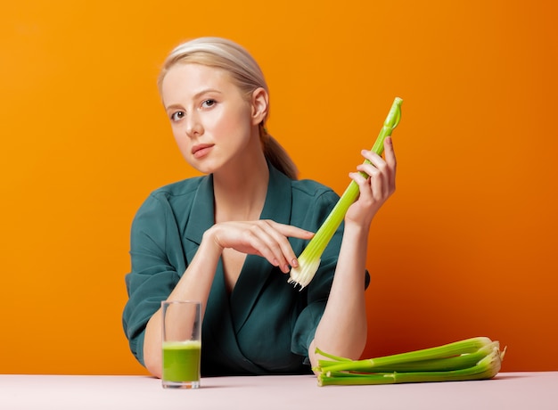 Stylish blonde sits at the table next to celery juice