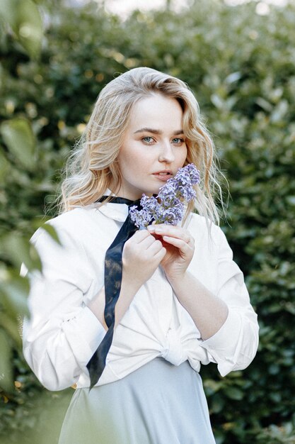 Stylish blonde woman in a blossoming garden