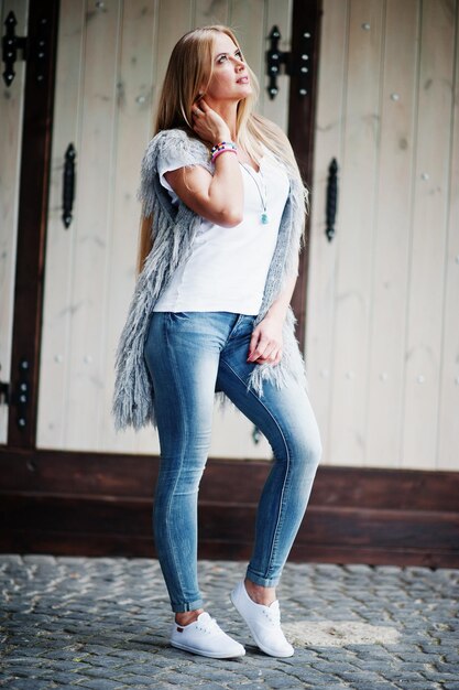 Photo stylish blonde woman wear at jeans and girl sleeveless with white shirt against street