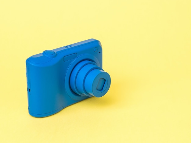 Photo stylish blue camera with extended lens on a yellow surface. stylish equipment for photo and video shooting.