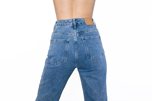 Stylish blue jeans with a high fit on a slender young woman standing with her back