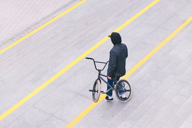 Стильный BMX байкер мальчик гуляет по городу. Концепция BMX. Вид сверху