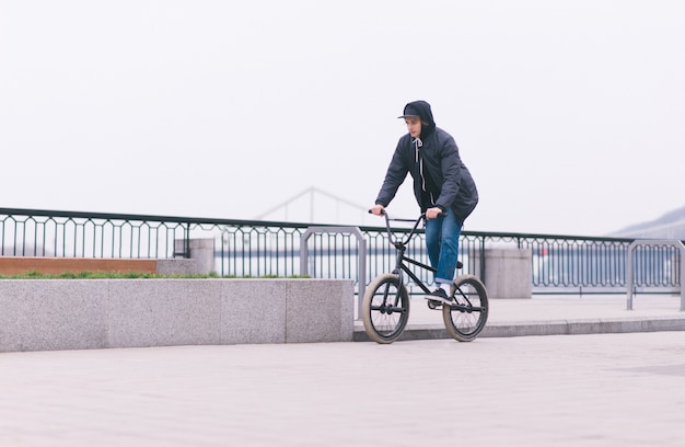 Стильный велосипедист BMX путешествует по набережной. Прогулка по BMX по городу. Концепция BMX. Уличная культура