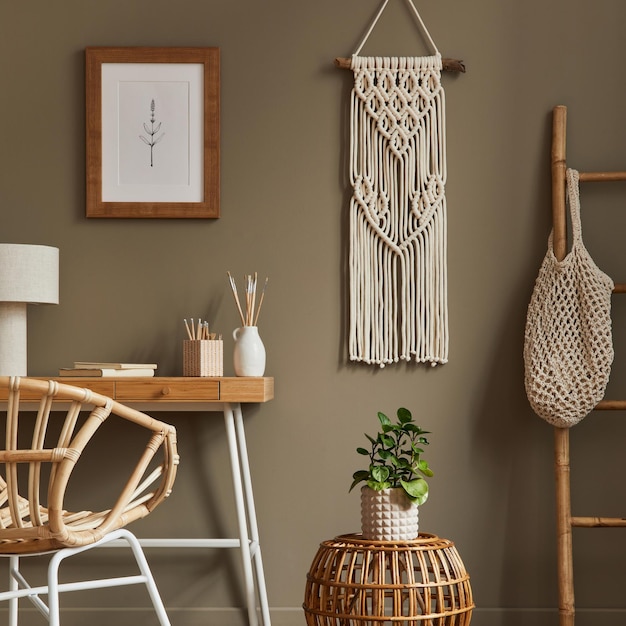 Stylish bohemian interior of home office space with wooden desk rattan armchair brown mock up poster frame macrame office supplies lamp decoration and elegant personal accessories in home decor