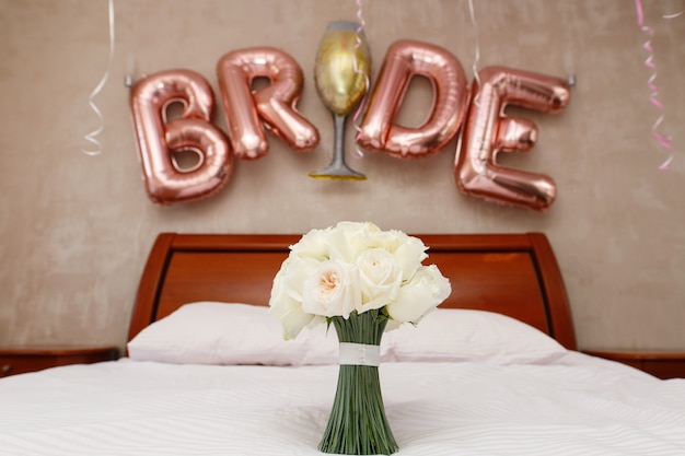 stylish bouquet of white roses in hotel room close up. bridal bouquet in bedroom with the inscription "bride"