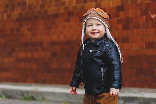 Stylish boy 3 years old in a leather jacket and brown trousers walks on the street Modern child Children's fashion Happy child