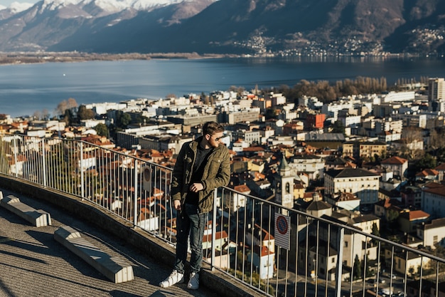 Stylish boy against the background of lake Lugano, Switzerland, mount Bre with snow on top.