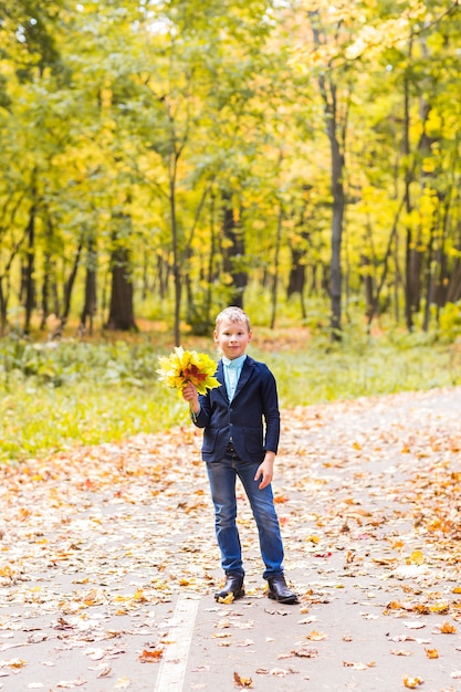 Stylish boy posing in autumn park with leaves