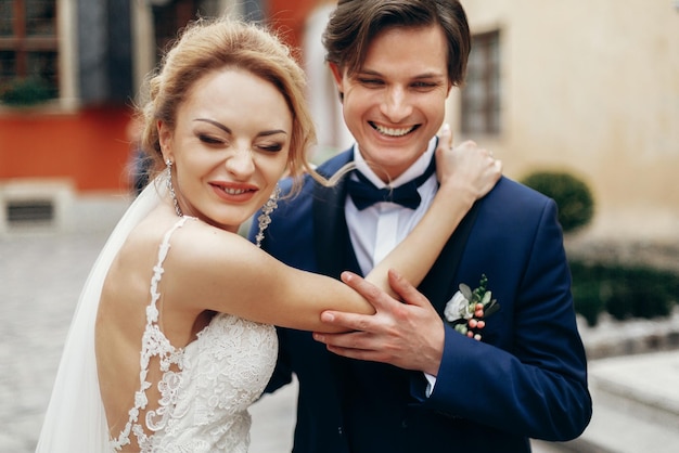 Stylish bride and groom dancing and embracing in city street
happy luxury wedding couple hugging at old building in light
romantic sensual moment woman and man smiling