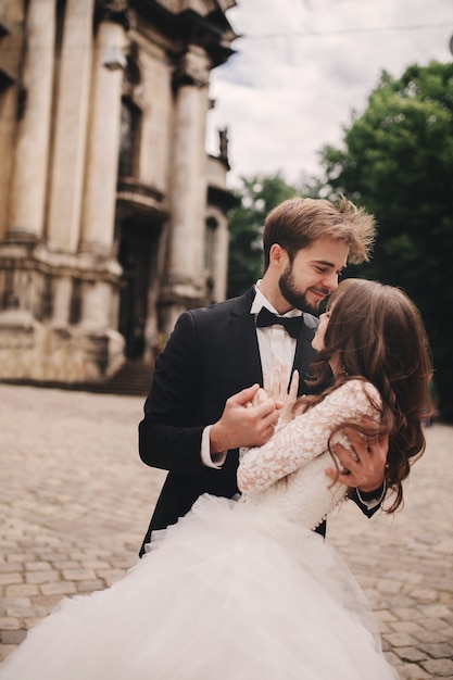 Foto elegante sposa e sposo che abbracciano delicatamente in via della città europea