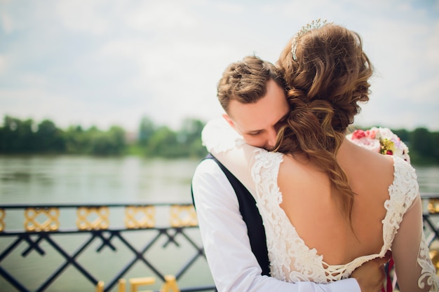 Stylish bride and groom posing on the background of the river.