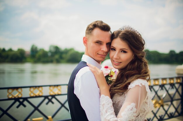 Sposa e sposo alla moda che posano sullo sfondo del fiume.