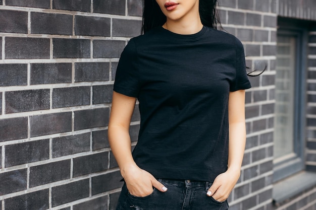 검은 티셔츠와 선글라스를 끼고 거리의 도시 천에 포즈를 취한 세련된 갈색 머리 아시아 소녀