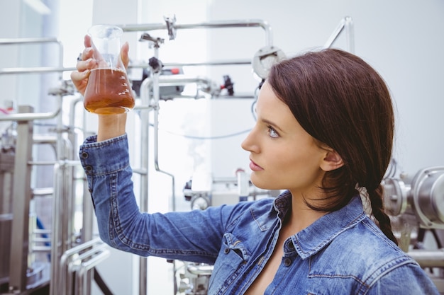 Stylish brunette in denim jacket looking at beaker of beer