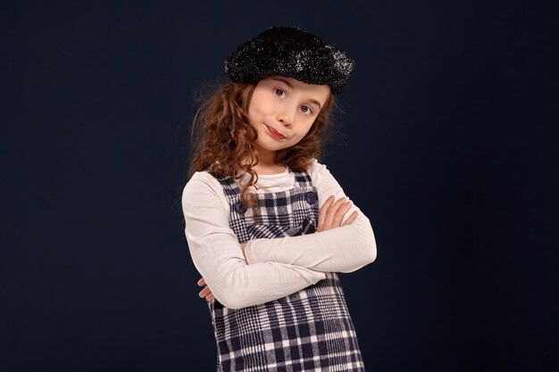 Stylish brunette kid is posing in studio on a black background childrens fashion