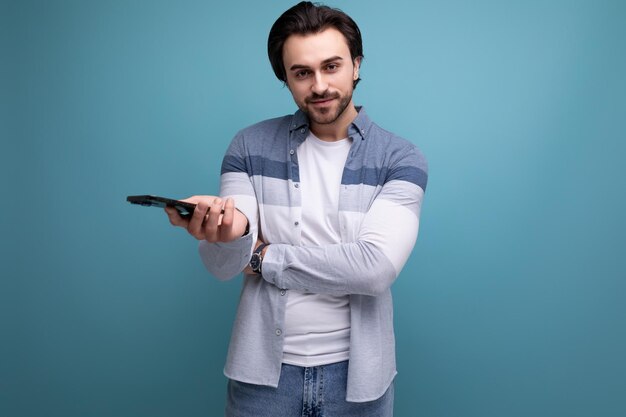 Stylish brunette man in a model appearance holds a smartphone in his hands