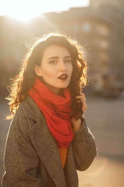 Stylish brunette model with lush hair posing in soft evening backlight at the avenue