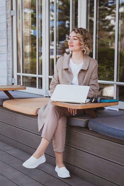 Stylish business woman in a street cafe working on laptop