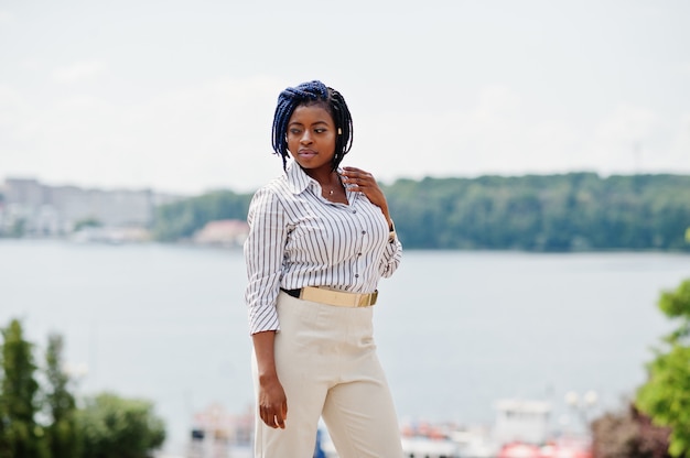 Stylish business woman at trousers and blouse posed outdoor against lake