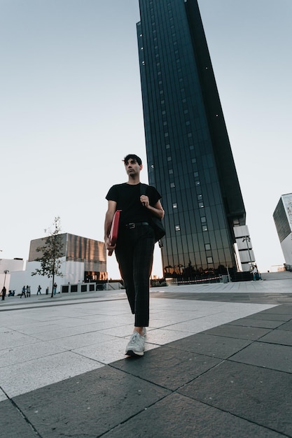 Stylish businessman student on the way to office during a
colourful sunset. business, education,lifestyle concept.serious
model with tshirt.copy space.big building scenery, banking and
administration.